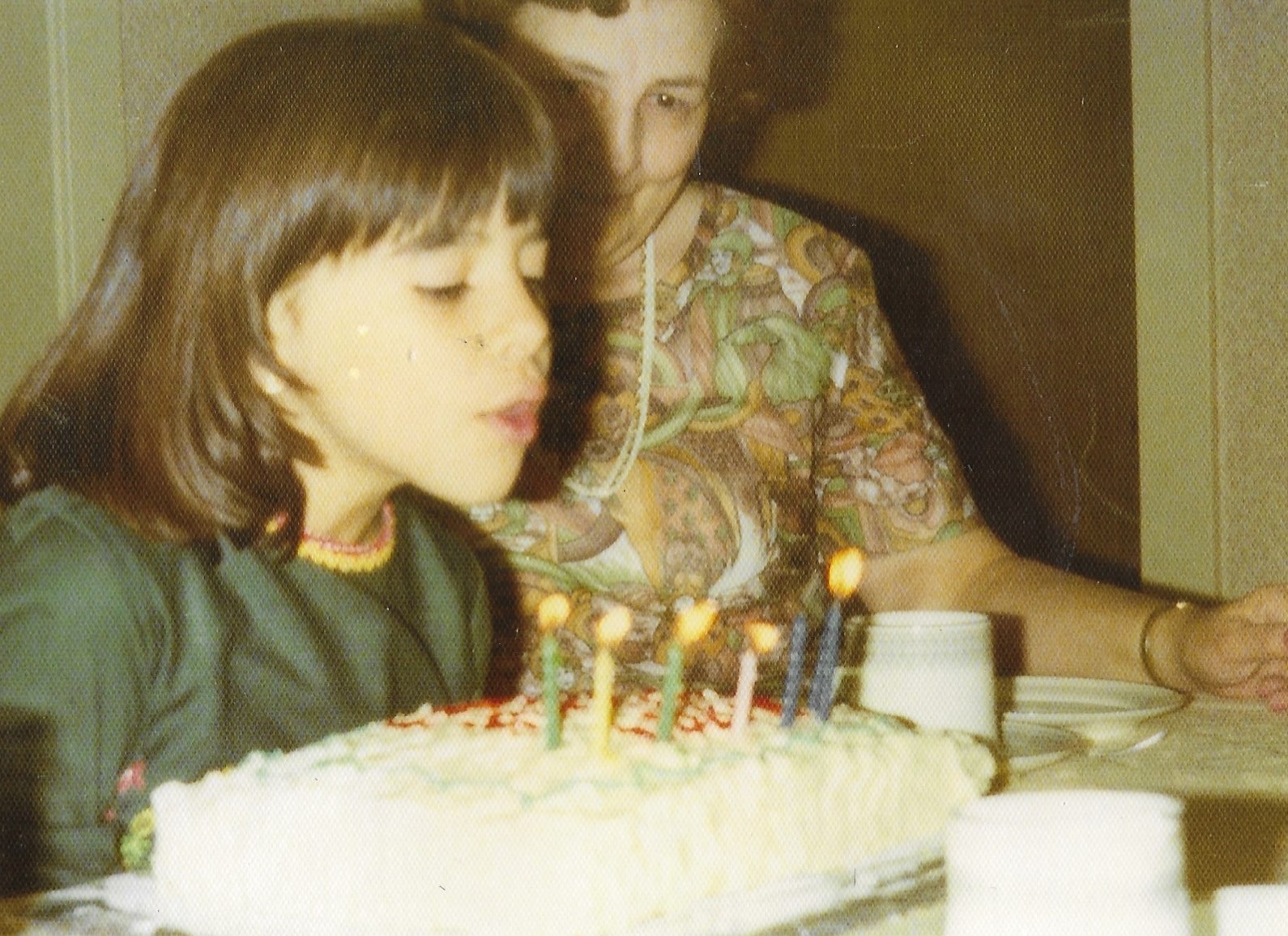 Child blowing out candles on a cake.