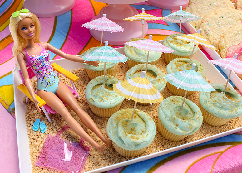 Beach Cupcakes on a graham cracker platter with Barbie sitting next to them