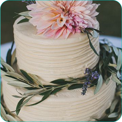 Two tier white wedding cake with flower topper